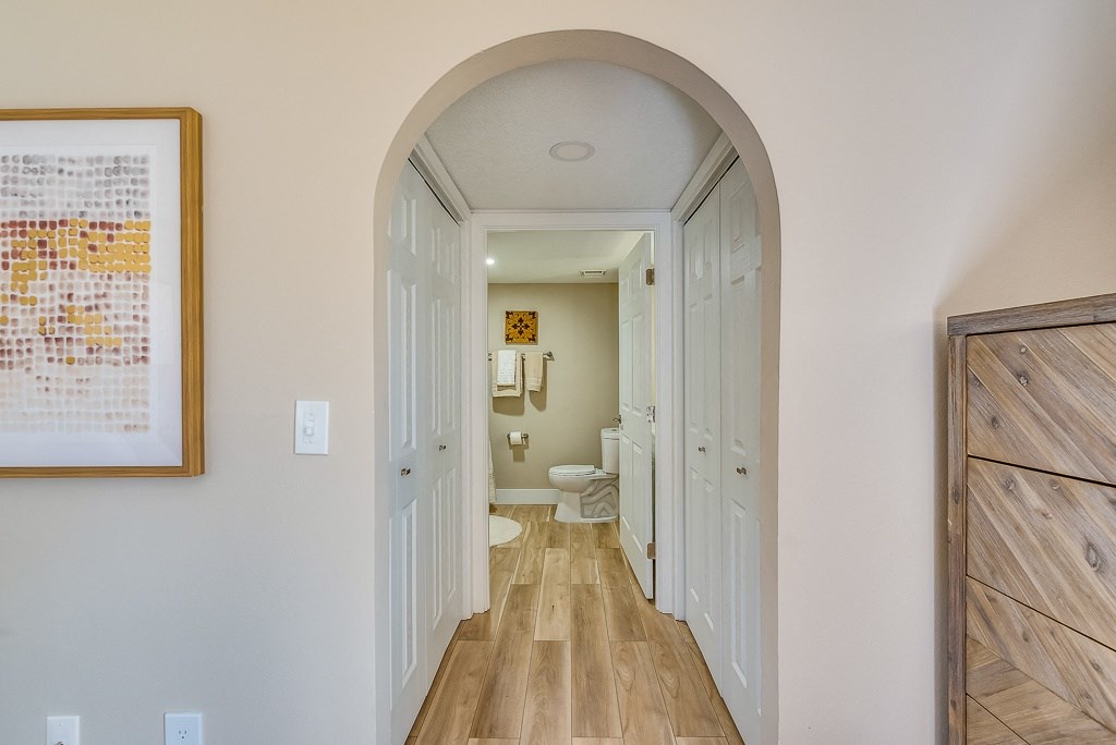a hallway with an arched doorway leading to a bathroom with a toilet and sink