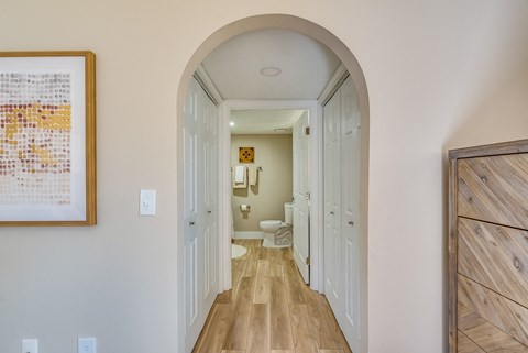 a hallway with an arched doorway leading to a bathroom with a toilet and sink