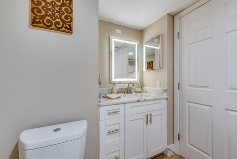 a bathroom with white cabinets and a white toilet