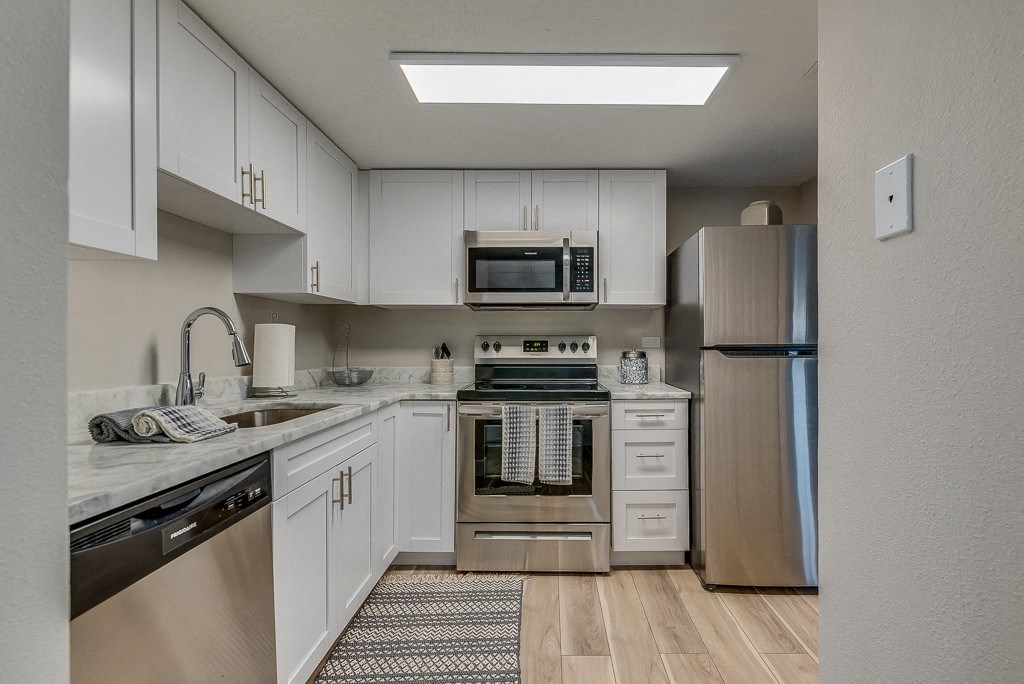 a kitchen with white cabinets and stainless steel appliances