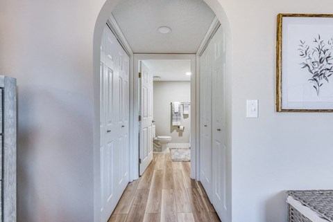 a hallway in a home with white walls and wood floors