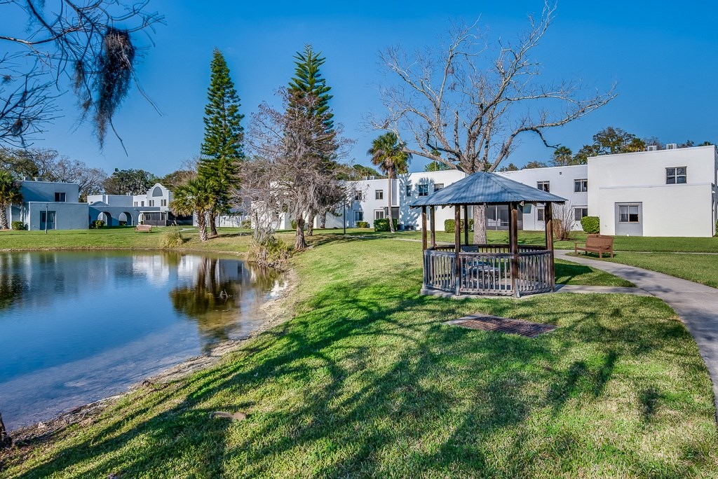 a gazebo sits next to a small pond in the middle of a grassy