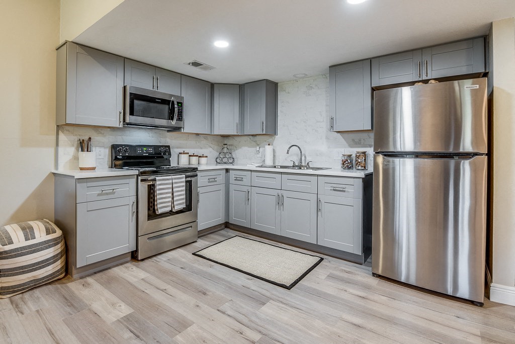 a kitchen with gray cabinets and stainless steel appliances