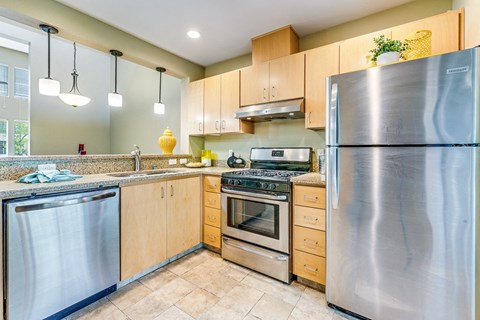 A modern kitchen with a stainless steel refrigerator, oven, and dishwasher.