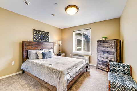 A bedroom with a bed, a nightstand, and a window.