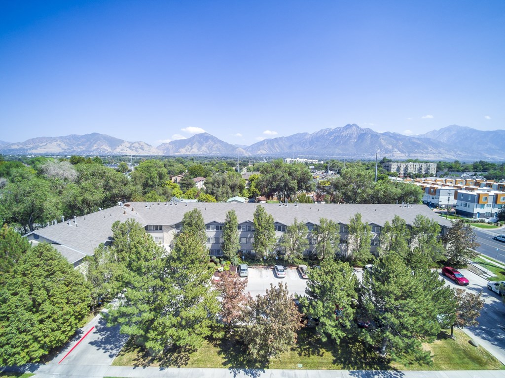 an aerial view of a building with trees and mountains in the background