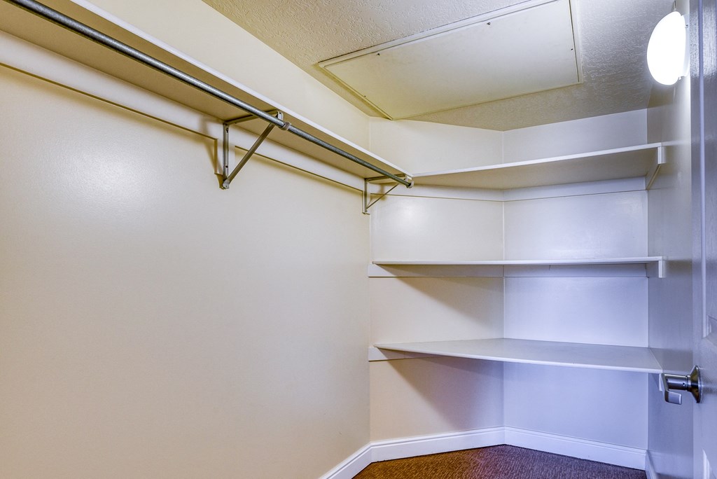 a walk in closet with white walls and shelves
