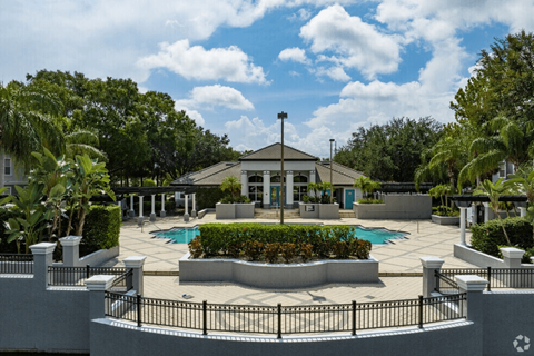 A pool area with a building in the background and a fence surrounding the pool.