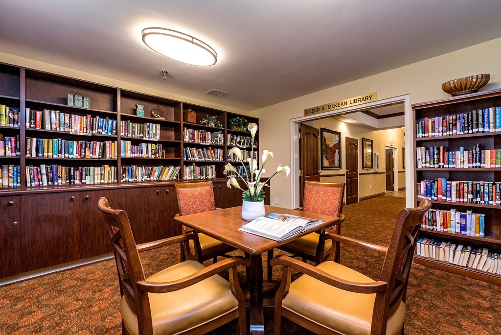 a library with a table and chairs and bookshelves