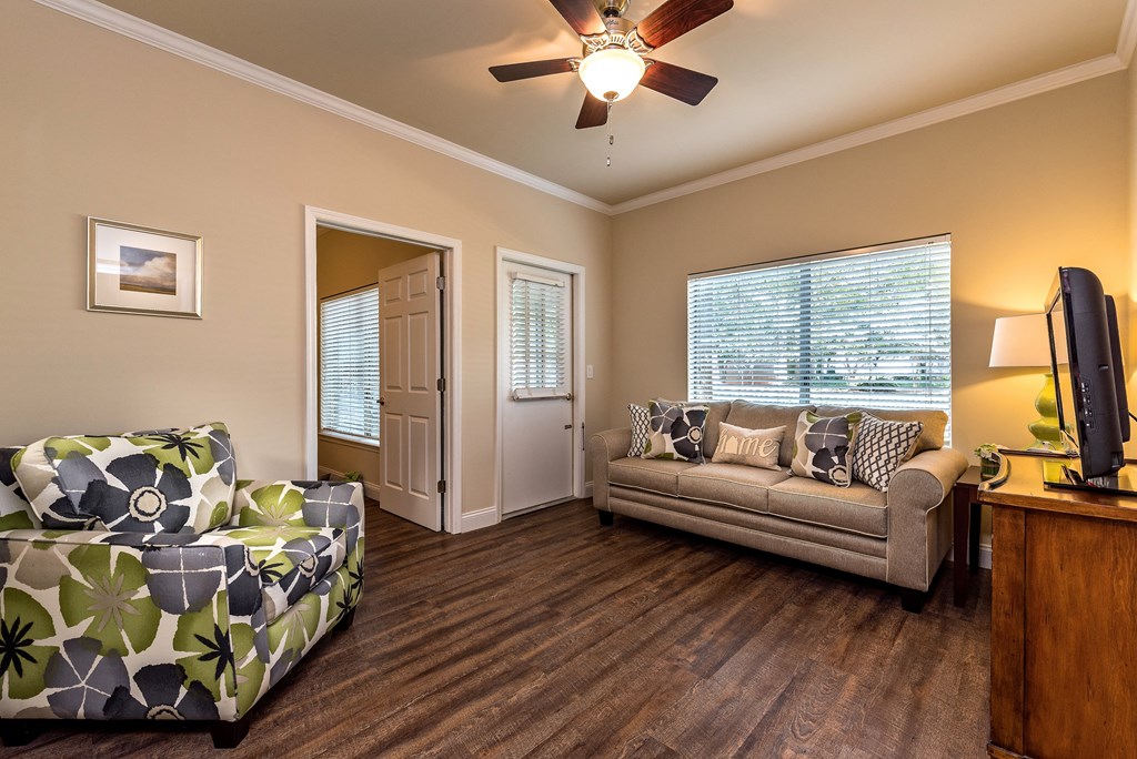 a living room with a couch and a chair and a ceiling fan