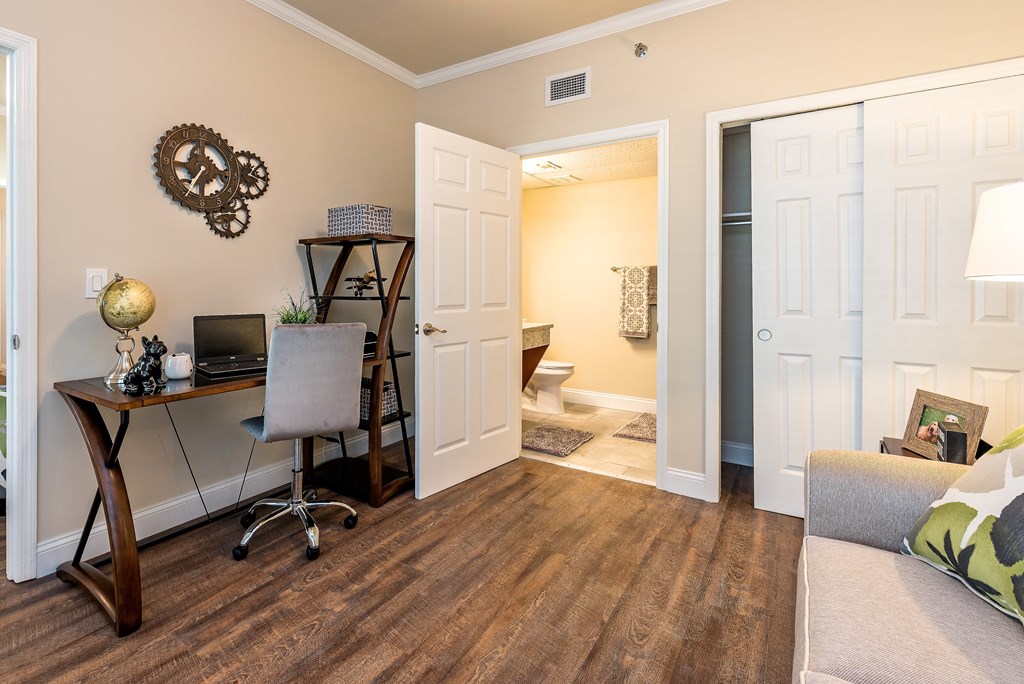a home office with a desk and a doorway to a bathroom