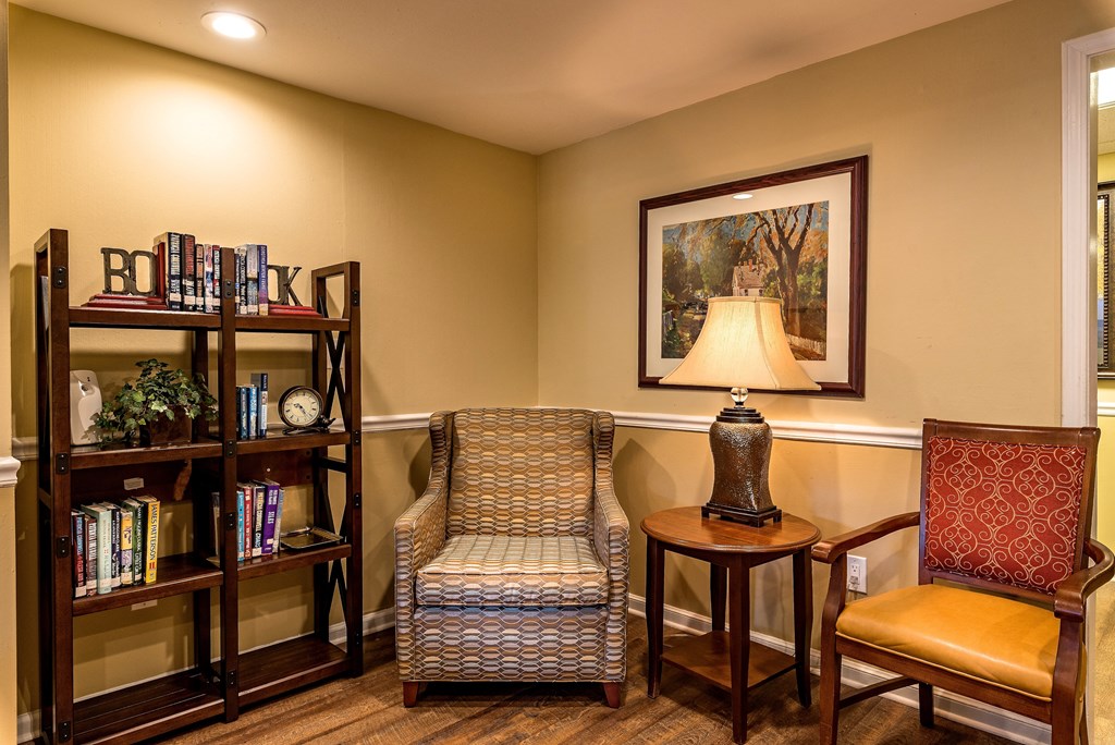 a living room with chairs and a table with a lamp