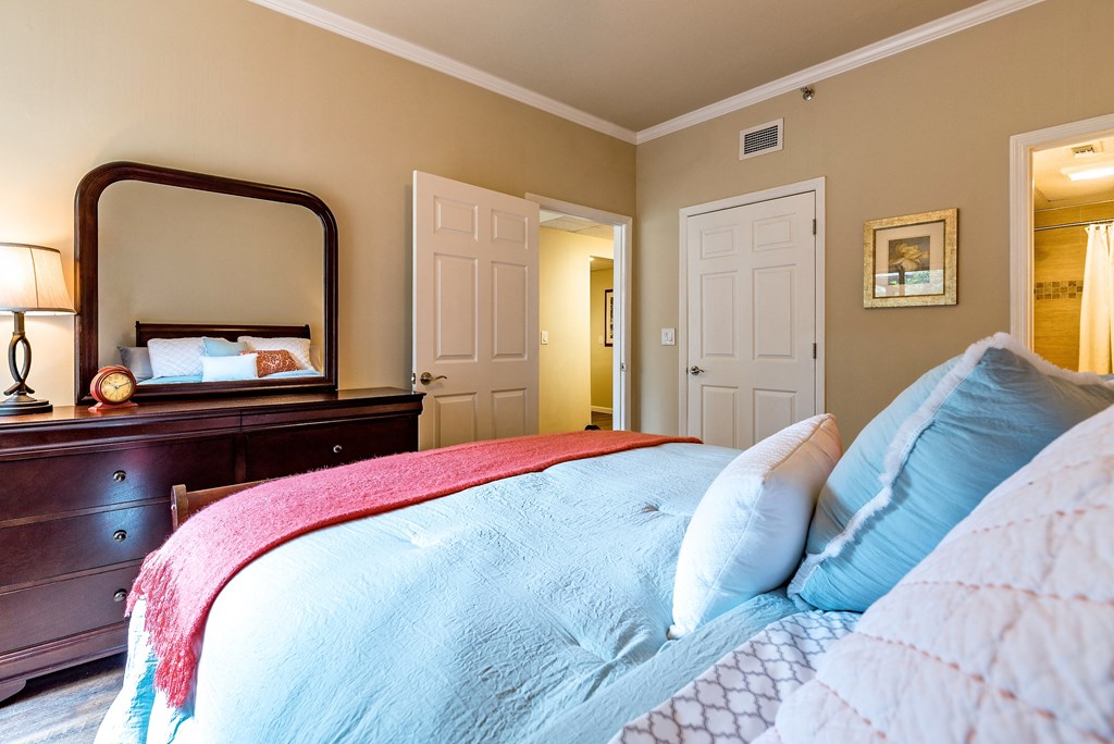 a bedroom with a bed and a dresser and a mirror