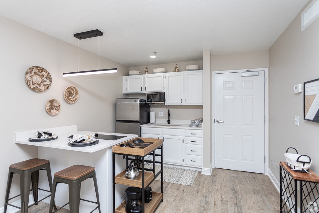 a white kitchen with a white counter top and a black refrigerator