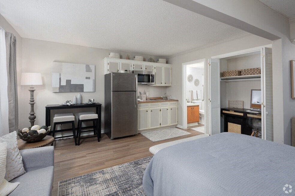 a bedroom with a bed and a kitchen with a refrigerator