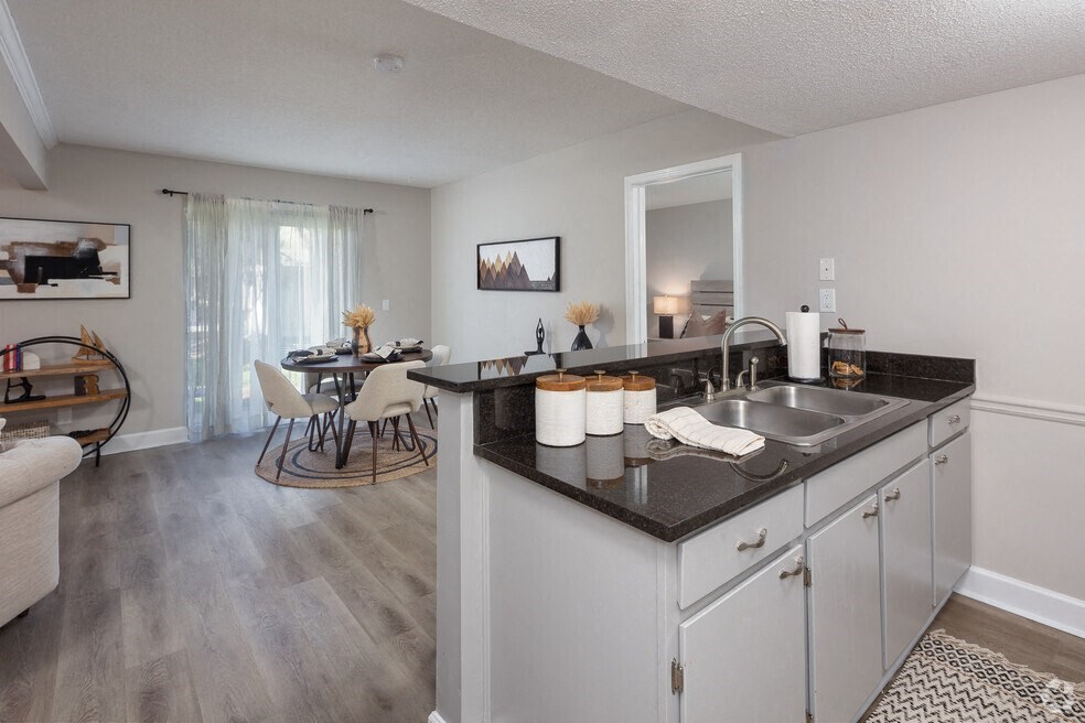 a kitchen with a sink and a dining room with a table and chairs