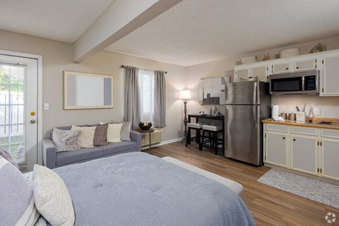 a bedroom with a bed and a kitchen with a refrigerator