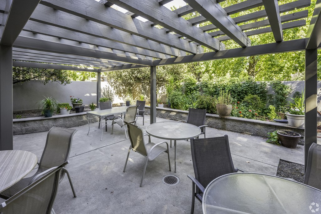 a patio with tables and chairs and a pergola