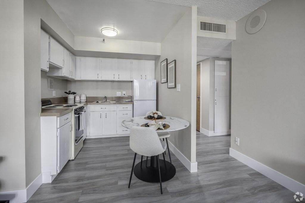 a kitchen with white cabinets and white appliances and a white table