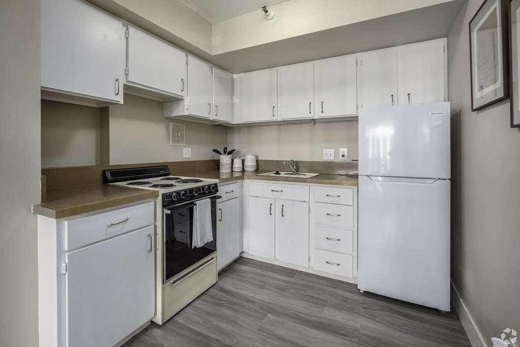 a kitchen with white cabinets and appliances and a white refrigerator