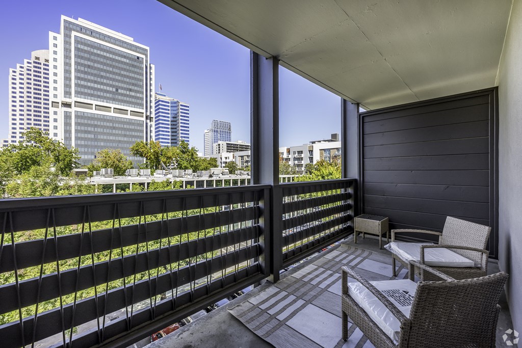 a balcony with two chairs and a view of the city