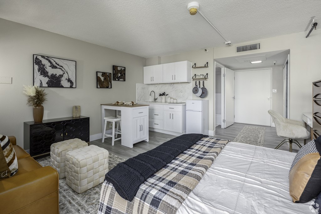 a bedroom with a bed and a kitchen with white cabinets