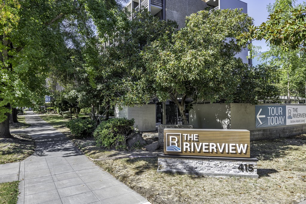 the riverview apartments sign in front of a sidewalk and trees