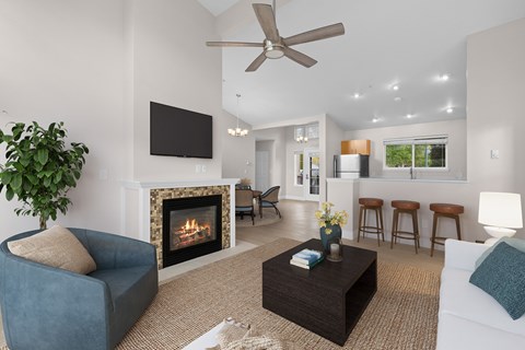 A living room with a fireplace, a blue chair, a white couch, and a ceiling fan.