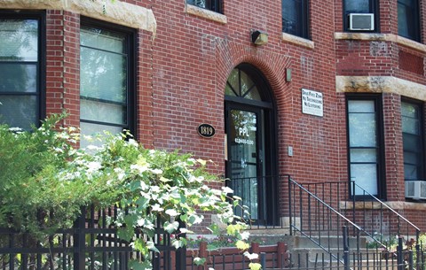 A red brick building with a black gate and a sign on the wall.