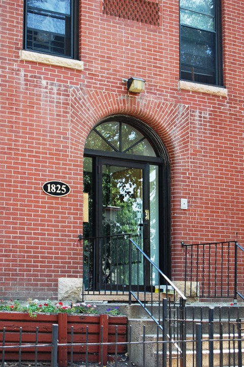 A red brick building with a black door and a number 1825 on the front.