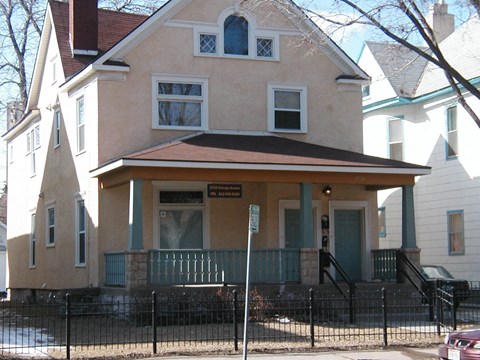 A two-story house with a green door and a sign on the front porch.