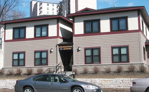 A grey car is parked in front of a building with a red and white striped awning.