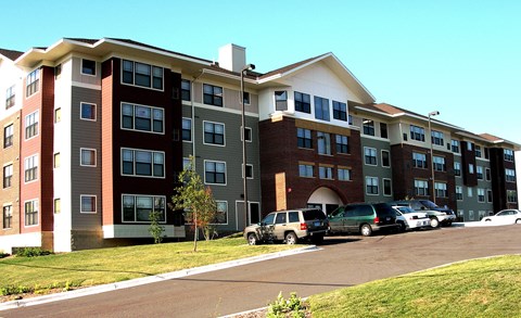 A large apartment complex with a parking lot in front.