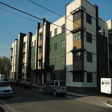A white car is parked in front of a multi-story building.