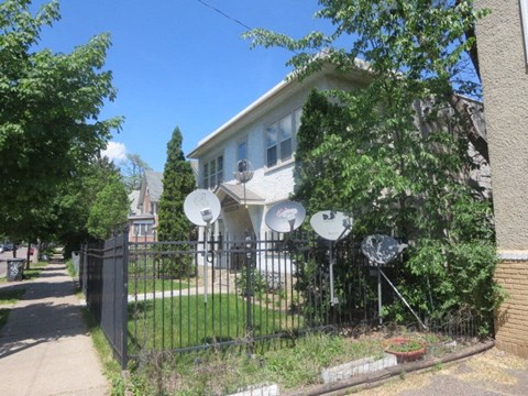 A house with a black fence and satellite dishes on the roof.