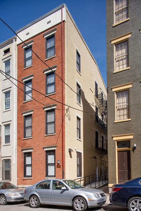 A silver car is parked in front of a red brick building.