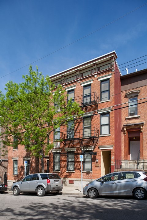 A red brick building with a tree in front of it.