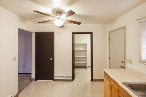 A kitchen with a fan on the ceiling and a sink on the counter.