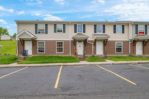 A row of townhouses with a parking lot in front.