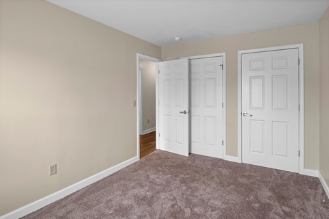 A room with carpeted floor and three doors.