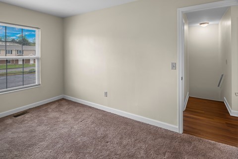 A room with a carpeted floor and a door leading to another room.
