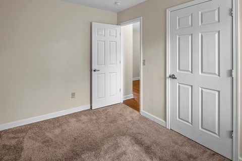 A room with a carpeted floor and two white doors.
