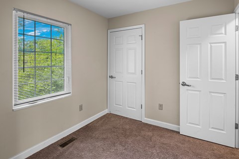A room with a window and two doors.