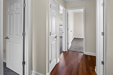 A hallway with white doors and a brown floor.