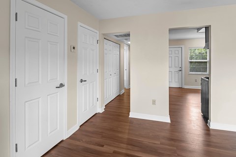 A long hallway with white doors and wood floors.