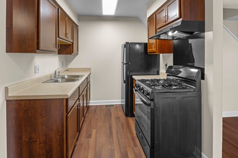 A kitchen with a black stove top oven and wooden cabinets.