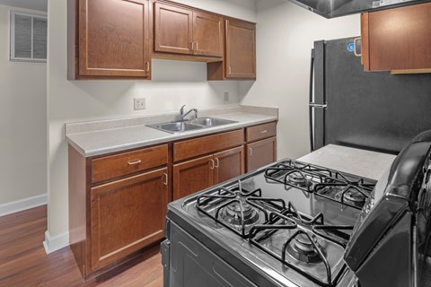 A kitchen with a black stove and wooden cabinets.