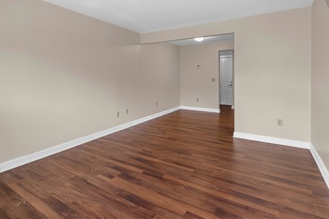 A room with wooden flooring and a door in the background.