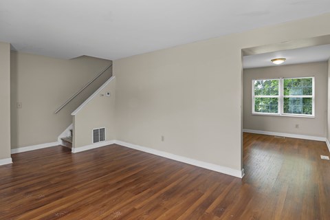 A room with wooden floors and a window with a view of trees.