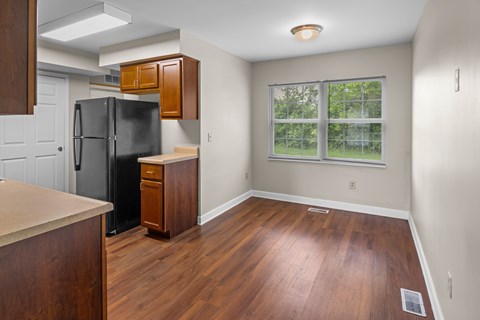 A kitchen with a black fridge and wooden floors.